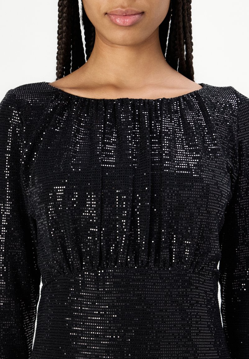 Czarna sukienka z cekinami, z długimi rękawami, zgromadzonym dekoltem i fakturowaną powierzchnią. Charakteryzuje się połyskiem i dopasowanym krojem.