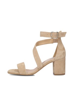 Beige suède sandalen met hak, open teen en gekruiste enkelbandjes met een metalen gesp en een gladde textuur.