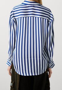 Camicia a righe blu e bianche con colletto, maniche lunghe e vestibilità comoda. Tessuto morbido con righe verticali.