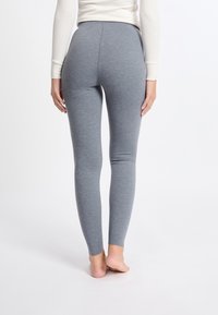 Grijze leggings gemaakt van een zachte, rekbare stof, met een hooglijn ontwerp en een gladde textuur, getoond vanaf de achterkant.