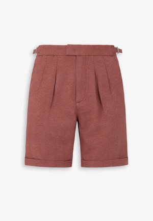 Pantaloncini sartoriali color ruggine con pieghe, orli risvoltati e cinturini laterali regolabili con fibbia su sfondo bianco.