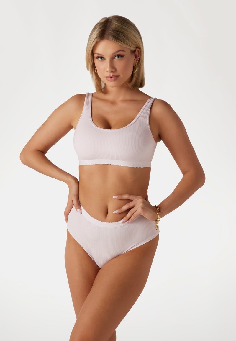 Lichtroze geribbelde bralette en hoog-waisted bikini set. Heeft een scoop halslijn, geschulpte randen en een zachte textuur. Minimalistisch ontwerp.