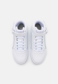 White high-top sneakers with a smooth leather finish, padded collar, front laces, and a Velcro strap. Subtle perforations on the toe.
