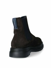 Stivale alla caviglia in suede marrone scuro con pannelli laterali elasticizzati e suola in gomma nera texturizzata. Presenta una linguetta blu sul retro.