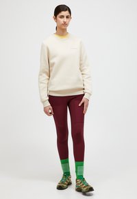 Felpa crema, leggings bordeaux, calzini a coste verdi. Design leggero e sportivo; la felpa ha polsini a costine; le scarpe presentano lacci multicolore.