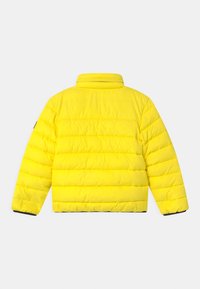 Žlutá péřová bunda s vysokým límcem, prošívaným designem a žebrovanými manžetami. Materiál má hladkou strukturu a je lehký.