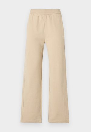 Μπεζ παντελόνια με φαρδιά μπατζάκια, ελαστική μέση και ελάχιστες ραφές, εμφανίζονται μπροστά σε απλό ανοιχτό φόντο.