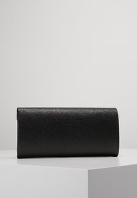 Musta tekonahasta valmistettu clutch, suorakulmainen muoto, teksturoitu pinta, sileät reunat, ilman näkyvää varustusta tai koristeluita.