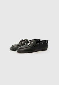 Schwarze Lederflachschuhe mit runder Zehenform, Schnürdetail mit silbernen Ösen und einem kleinen Logoakzent auf der Vorderseite.