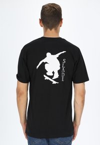 Sort kortærmet t-shirt med et hvidt skateboarder-grafik og ordet "SLADE" i hvid tekst på ryggen.