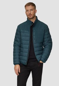 Pufferjack in diep teal, met een rits aan de voorkant, horizontale stiksels en een borstzak. De stof heeft een soepele textuur.