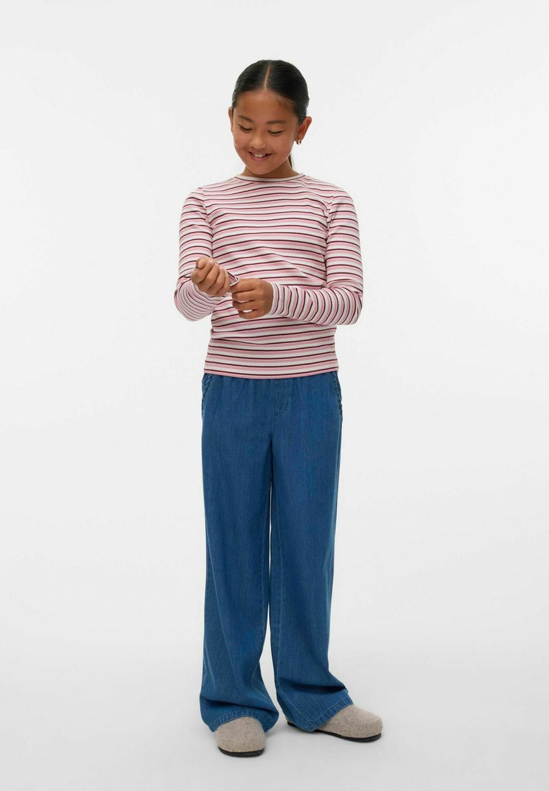 Camicia a maniche lunghe a righe rosse e bianche abbinata a pantaloni larghi blu chiaro e pantofole grigie. La camicia presenta un collo a giro e una vestibilità aderente.