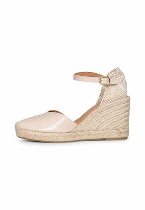 Alpargata beige con cuña, suela trenzada de yute, punta cerrada, talón de tela a cuadros y tira en el tobillo con hebilla dorada.