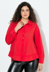 Rode katoenen langemouwen shirt met een knoopsluiting aan de voorkant, met een gerimpelde zoom en een klassieke kraag. Draagt met zwarte glanzende leggings.