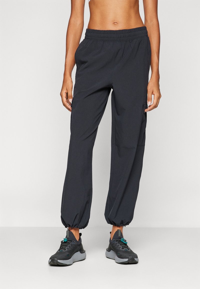 Zwarte, lichte joggingsbroek met een elastische tailleband, taps toelopende boorden en zijzakken. Het materiaal lijkt glad en ademend.