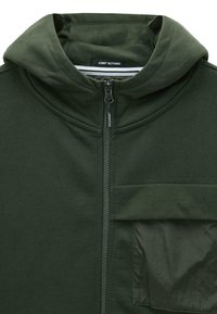 Donkergroen ritshoodie met een gevoerde capuchon, een voorzak met een glanzende textuur en een gladde stofafwerking. Het label zegt "ADMIT NOTHING."