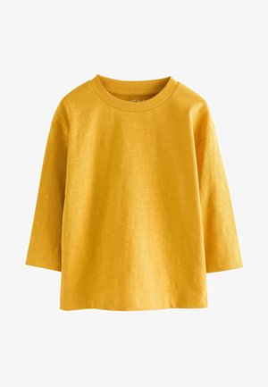 Żółta bluzka z długim rękawem, wykonana z miękkiego materiału, z okrągłym dekoltem i luźnym krojem, o gładkiej fakturze i minimalnych detalach szycia.