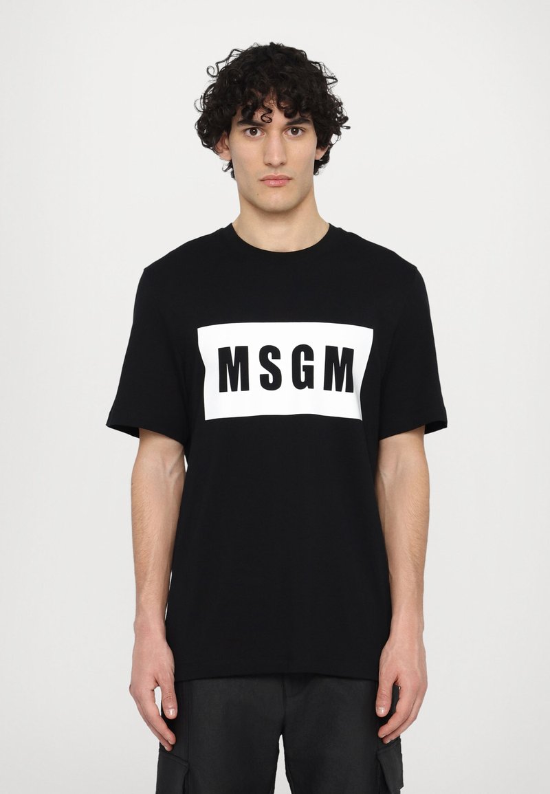 Svart bomullströja med kort ärm, med en vit rektangulär grafisk design med texten "MSGM" i feta svarta bokstäver.