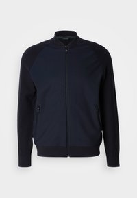 Mornarska zip-up jakna z visokim ovratnikom, raglan rokavi, dvema sprednjima žepoma z zadrgo in rebrastimi zapestji ter robom. Gladka tkanina z kontrastnimi strukturami.