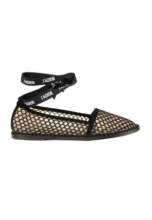 Chaussure plate noire avec une superposition de maille dorée et des liens de ruban noirs à la cheville imprimés du texte J’ADIOR.