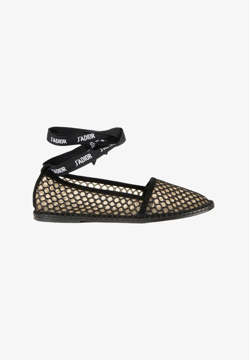 Chaussure plate noire avec une superposition de maille dorée et des liens de ruban noirs à la cheville imprimés du texte J’ADIOR.