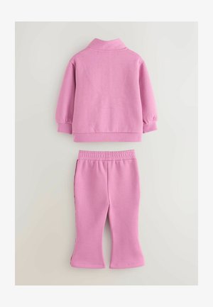 Roza dvodijelna odjeća koja se sastoji od pulovera s ovratnikom i rukavima s naramenicama, uparenog s hlačama na elastiku s proširenim rubovima.