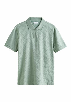 Jasnozielona koszulka polo z krótkim rękawem, teksturowanym falistym wzorem i zamkiem błyskawicznym przy kołnierzu.
