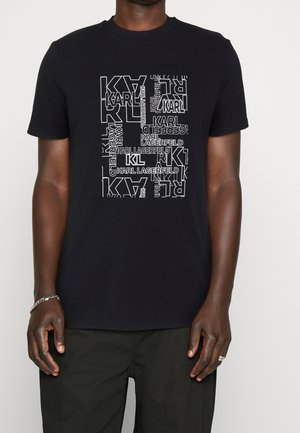 Zwarte t-shirt met witte grafische tekstblok dat herhaaldelijk "KARL LAGERFELD" en "KL" toont in verschillende lettertypes en oriëntaties.