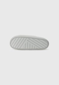 Grey rubber sneaker sole with a textured grip pattern, featuring diagonal and horizontal grooves and a rounded toe shape.