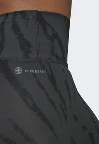 Hoge taille zwarte leggings met een textuur en een abstract donker patroon. Bevat het AEROREADY-logo en vlakke naden voor een soepele afwerking.