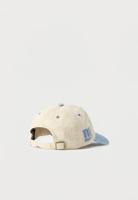 Μπεζ και ανοιχτό μπλε καπέλο μπέιζμπολ με ρυθμιζόμενο λουρί και κεντημένο μπλε λογότυπο "NY" στην πλευρά, σε απλό λευκό φόντο.