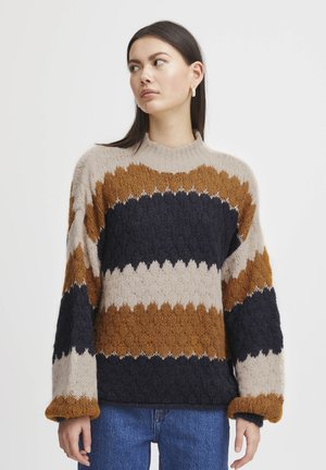 Knit sweater featuring a wide zigzag pattern in brown, navy, beige, and cream. Loose fit with a ribbed neckline and oversized sleeves.