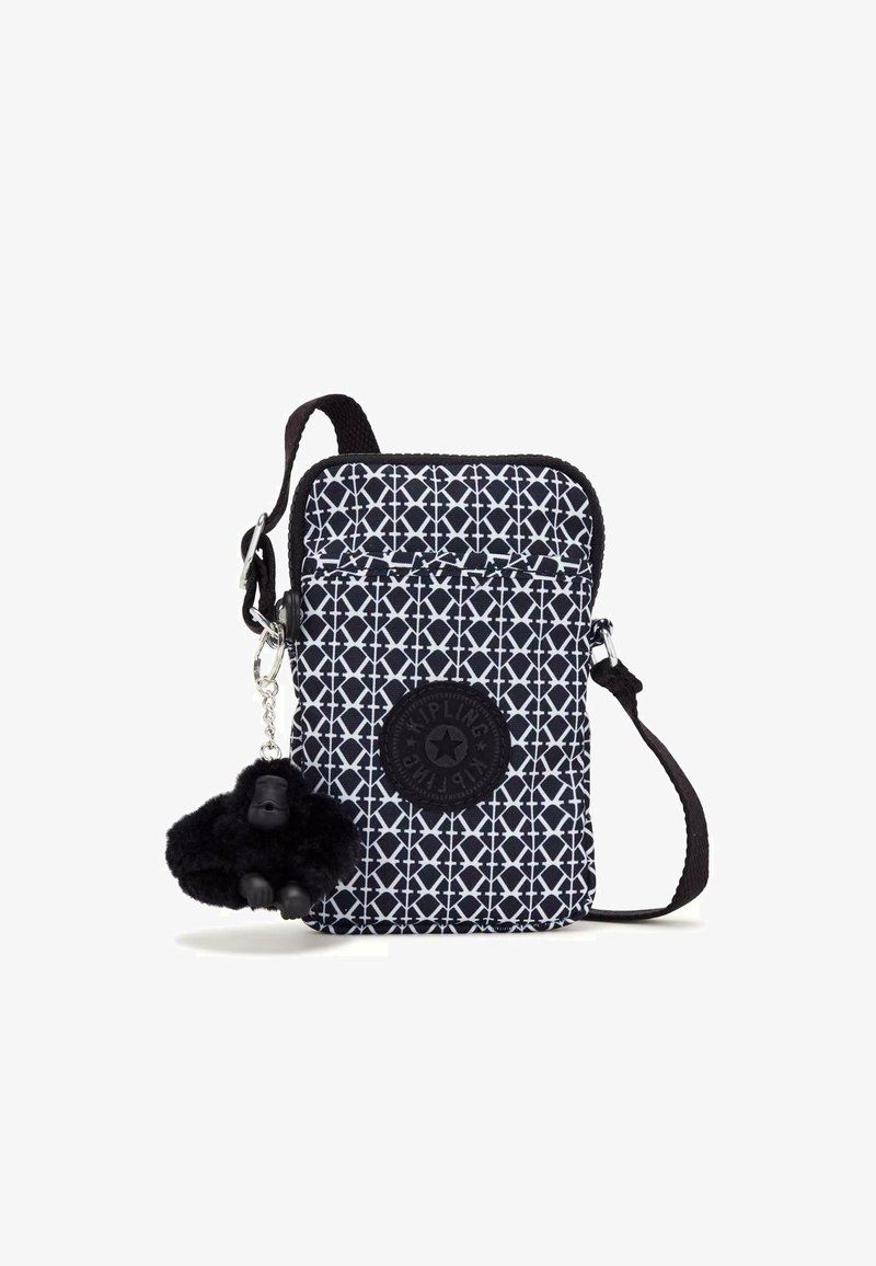 Black and white patterned crossbody bag made of fabric, featuring a round brand logo and a black pom-pom monkey keychain attachment.