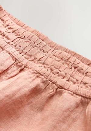 Cintura elastica di un rosa chiaro con texture arricciata. Il tessuto appare morbido e leggermente spiegazzato, indicando uno stile informale e traspirante.