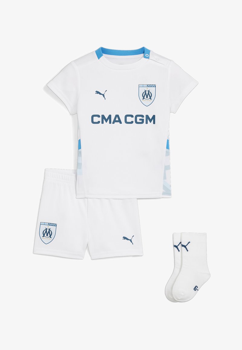 El conjunto de deportes juvenil blanco incluye una camiseta de manga corta, pantalones cortos y calcetas. Presenta acentos azules, logotipos y una cinturilla elástica.