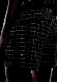 Mustat shortsit, joissa on valkoinen ruutukuvio, joustava vyötärö ja logoyksityiskohta. Kangas vaikuttaa olevan tekstuuriin liittyvä, ja näkyvissä on ompelusaumat.