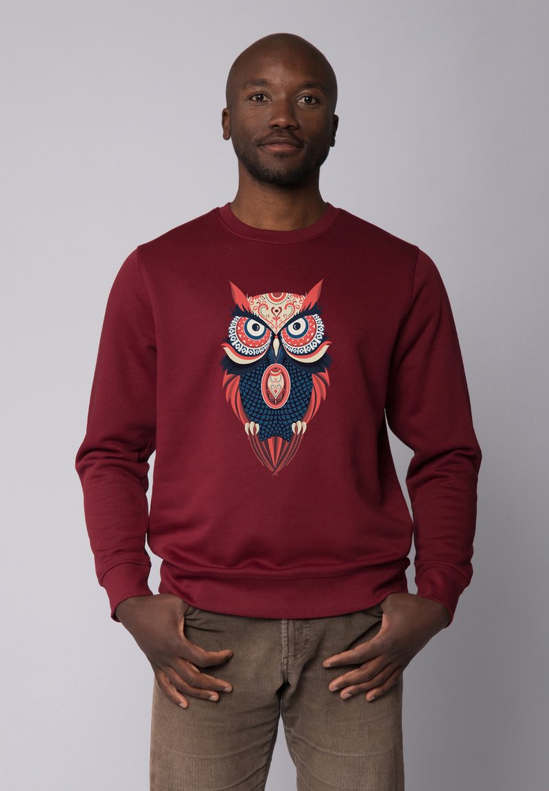 Bordeaux sweatshirt met een grote uilafbeelding met ingewikkelde blauwe en rode patronen. Ribgebreide manchetten en tailleband accentueren het ontwerp.