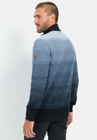 Herrenpullover mit einem Farbverlauf von Hellblau zu Marineblau. Strukturierter Strickstoff mit gerippten Bündchen und Saum, bracher Logopatch am Ärmel.