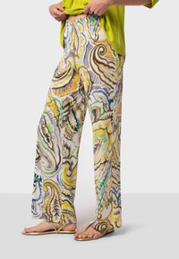 Pantalons larges légers à motifs avec des tourbillon en beige, jaune, bleu et vert. Tissu lisse avec une coupe décontractée et des poches latérales.