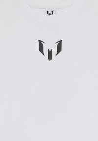 T-shirt en coton blanc avec un logo graphique noir au centre. Encolure ronde simple, manches courtes, texture lisse et sans embellissements supplémentaires.