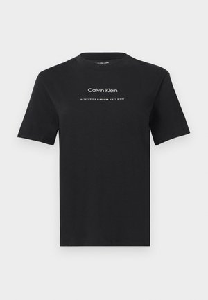 Melna īsroku krekla T-krekls ar apaļu kaklu, uz krūtīm centrēts baltā krāsā ar tekstu "Calvin Klein" un "Established Nineteen Sixty Eight".