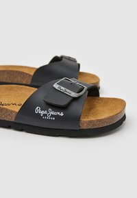 Svarta lädersandaler med korksula, prydda med en silverfärgad spänne och "Pepe Jeans London"-logotyp i vitt på remmen. Texturerat innersula.