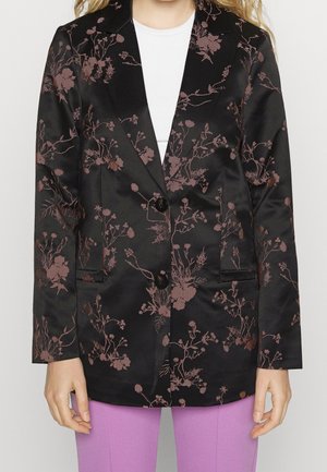 Sort satinblazer med lyserøde blomsterprint, båret over en hvid top, kombineret med lavendelfarvede bukser.