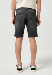 Shorts de mezclilla en gris oscuro con un corte regular, que cuentan con un diseño de cinco bolsillos, detalles de costura y un parche de marca en la cintura trasera.
