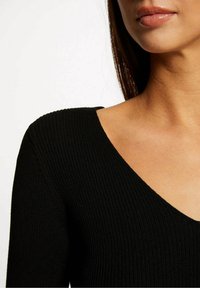 Czarny prążkowany top z dzianiny z głębokim dekoltem w kształcie litery V, slim fit i gładką fakturą. Odpowiedni do casualowych lub warstwowych stylizacji.