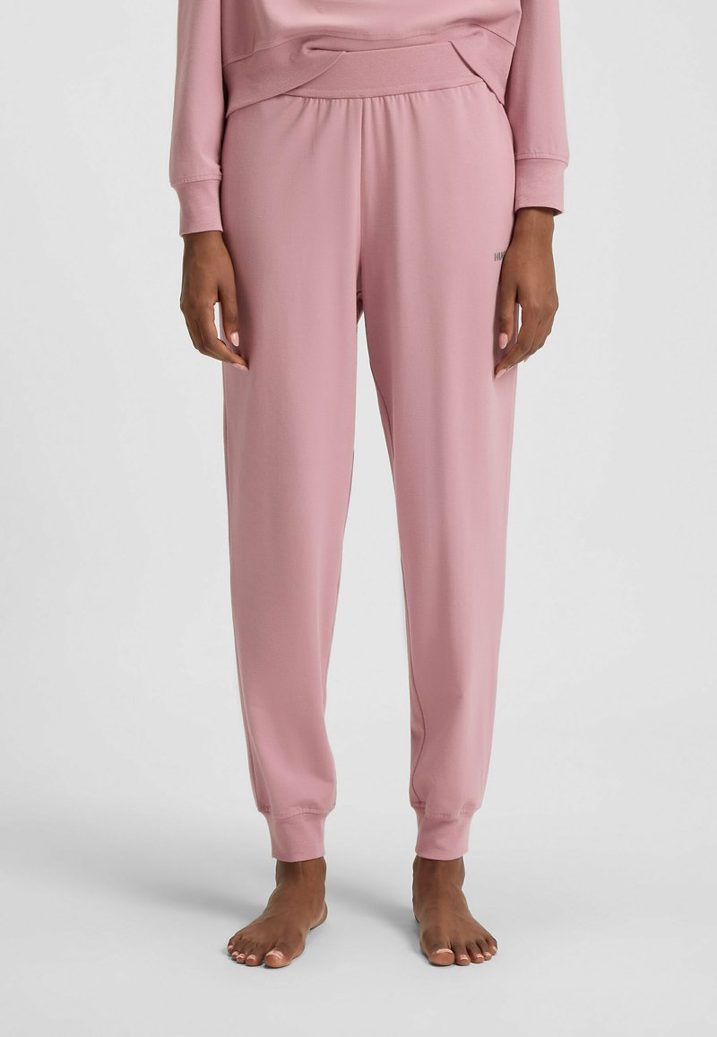 Pantalons de jogging roses en tissu doux, avec une taille élastique, des jambes fuselées et des ourlets à bord côtelé. Détail de marque minimal à l'avant.