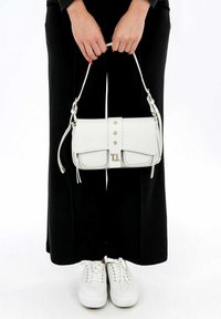 Bolso de mano de cuero blanco con cierre de solapa, tres remaches metálicos y una correa para el hombro. Presenta una textura suave y acentos en tono dorado.