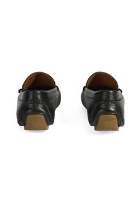 Zwarte leren loafers met een gladde textuur en een ronde neus, met een lage beige hak en subtiele stikdetails aan de achterkant.