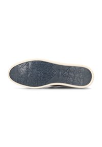 Suela de goma negra con un patrón texturizado; borde color crema. Presenta formas geométricas para proporcionar tracción en las superficies de caminata.