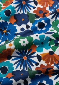 Floral fabric featuring a variety of colorful flowers in blue, green, orange, and white on a textured white background.